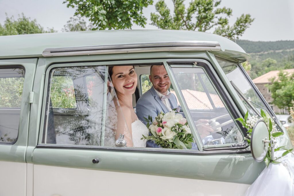 Mariés souriants à l'intérieur d'un van combi Volkswagen vintage vert lors d'un mariage dans le Gard.